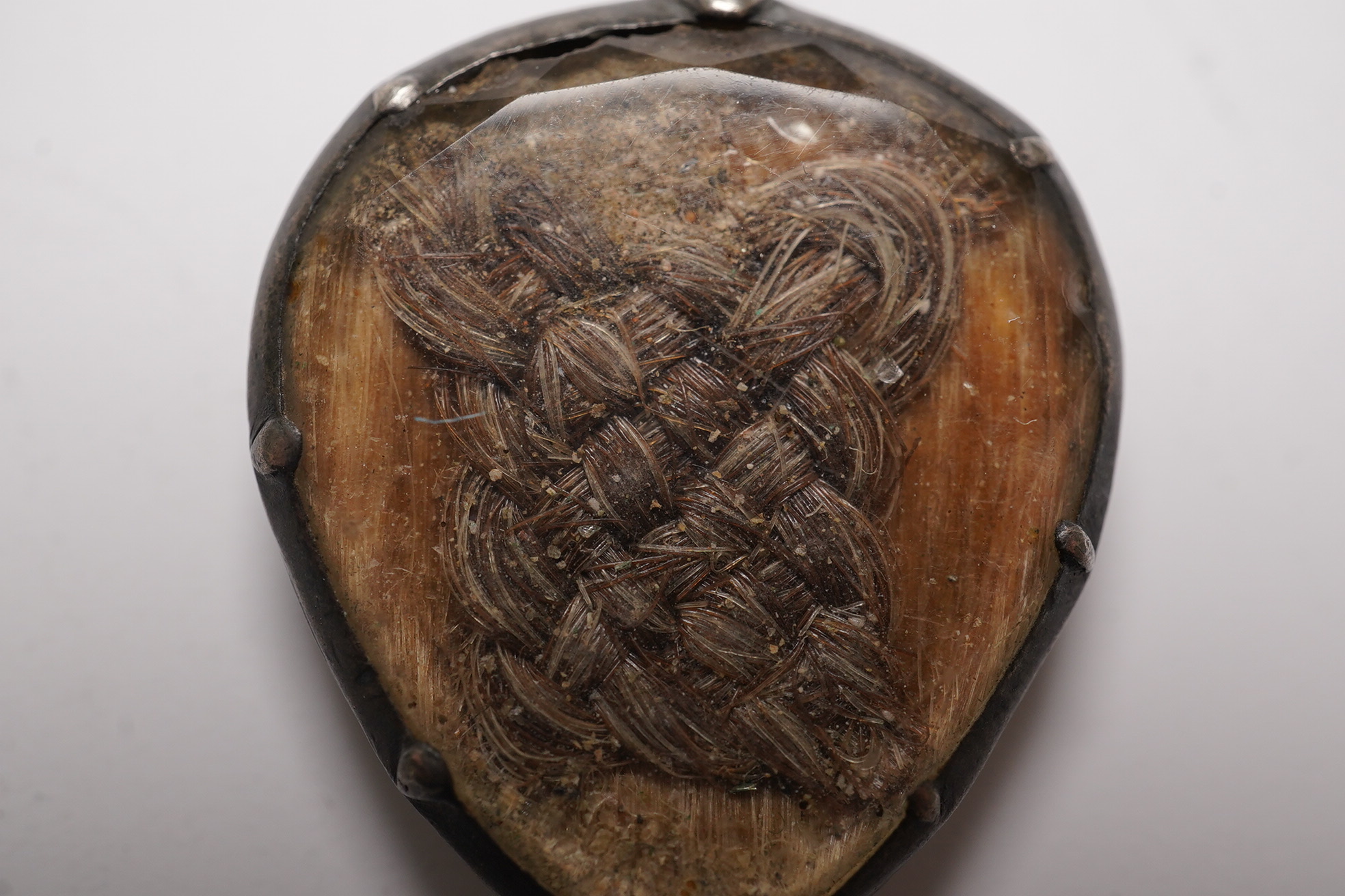 An 18th century gilt metal heart shaped mourning pendant, with engraved inscription, 'CARna DERBY DIED DEC 11th, 1762' and plaited hair beneath a glazed panel verso, 27mm.